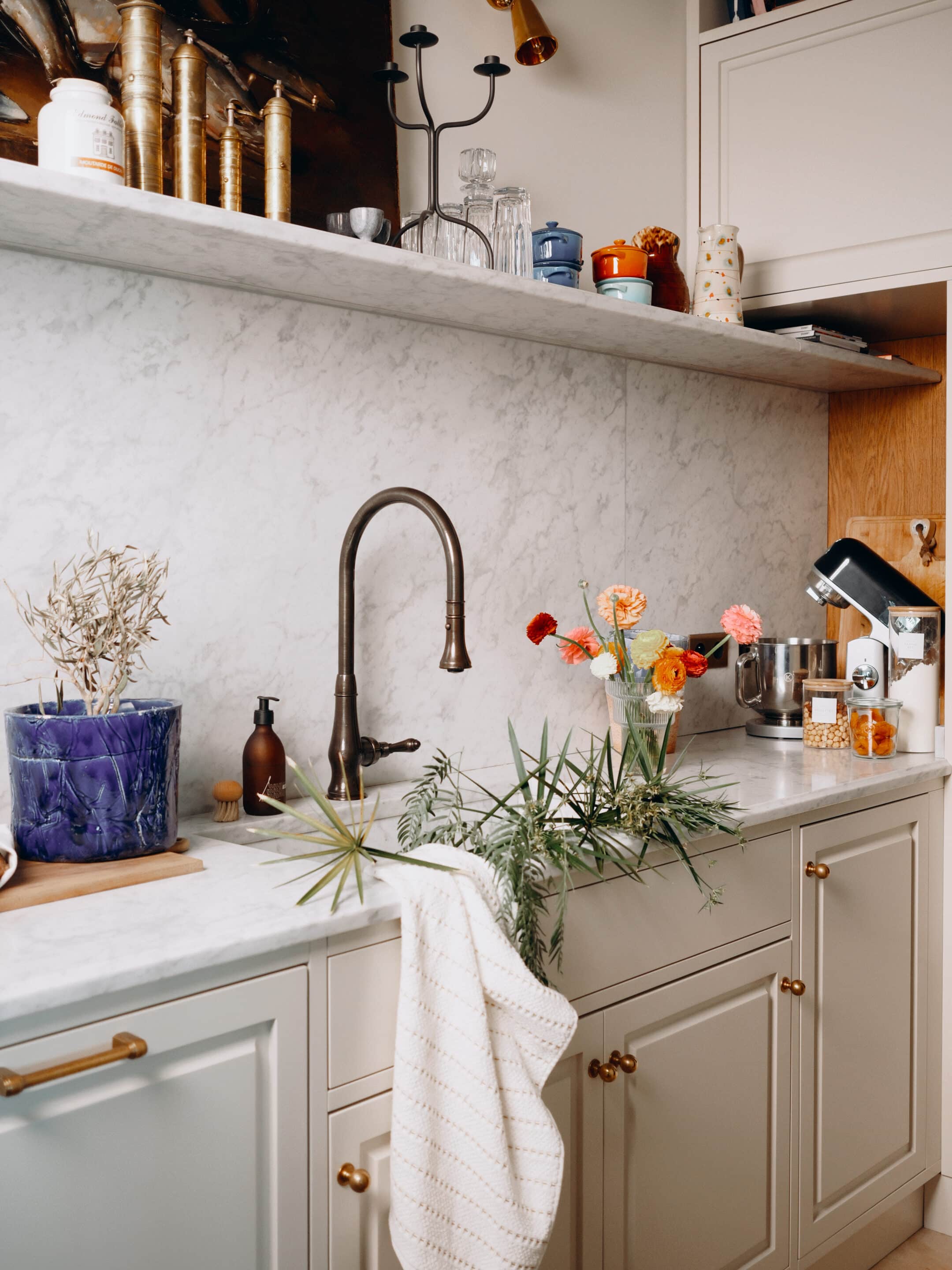 An eclectic ensemble of treasures on the marble floating shelf  glows under vintage 1970s German brass sconces from 1stDibs.