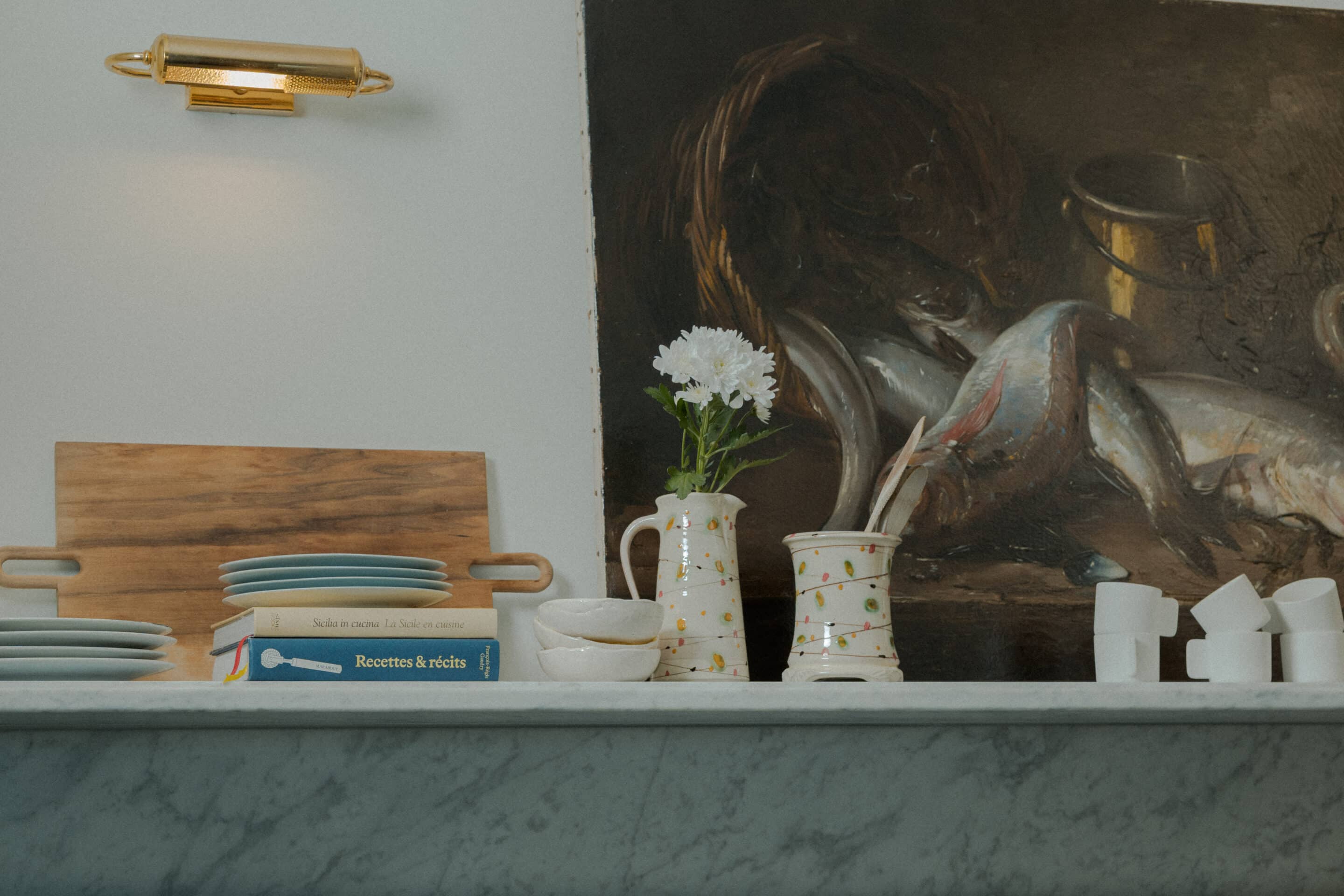 A tailor-made fireplace by Belgian brand Metalfire, defined by minimalist lines, anchors the room as a striking centerpiece, its flames coming alive in the winter months. The jewel-like side table features a glass top resting gracefully on an architectural base finished in sophisticated gold. Easy to move around, the occasional table  becomes an essential element of cocktail hour